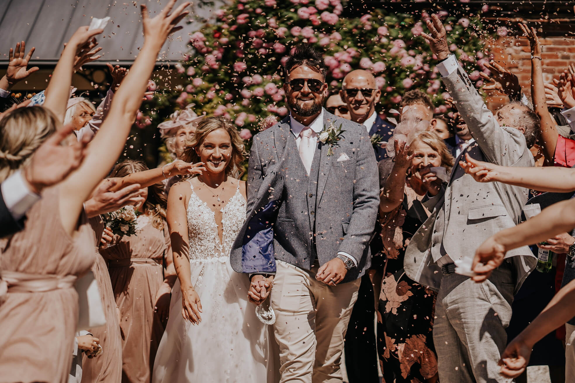 bride and groom leaving their wedding at St Johns House in Lichfield with their guests throwing confetti