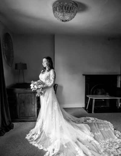 Black and white image of a bride in her dress with the train spread behind
