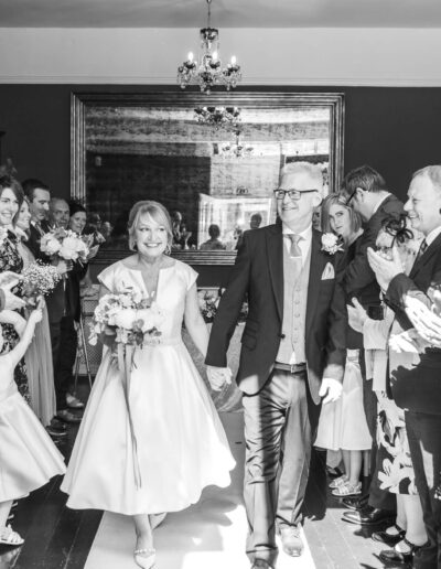 Black and white image of bride and groom leaving ceremony at St Johns House in Lichfield