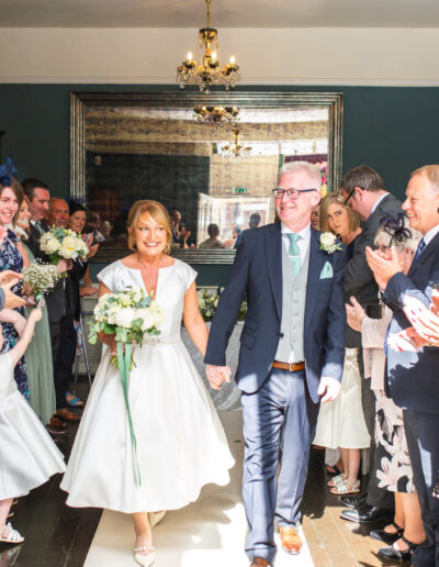 Bride and groom walking down the aisle in the ceremony room of St Johns House in Lichfield