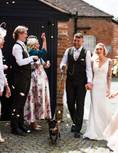 Bride and groom arrive at their wedding reception with their guests throwing confetti
