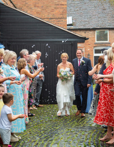 Bride and groom arrive at their wedding reception to a crowd of guests throwing confetti at St Johns House in Lichfield