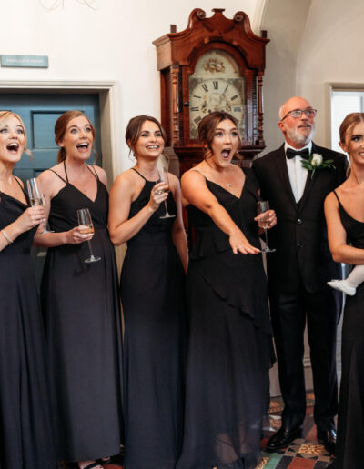 Bridal party reacting to the bride walking down the stairs of St Johns House in Lichfield