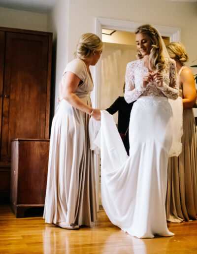 Bridal party preparing a bride and her dress